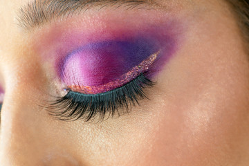Naklejka premium A close up of a beautiful purple eye makeup with glitter and multicolor transitions.