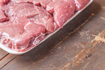 packaging of raw meat on a wooden table close up