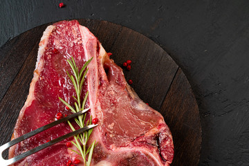 Raw t-bone steak with rosemary, pepper. Prepared for cooking. Close up.