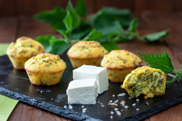 Fresh homemade muffins with cheese and nettle on wooden table. Healthy snack muffins with feta cheese and nettle.