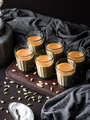 Indian chai in glass cups with metal kettle and other masalas to make the tea