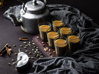 Indian chai in glass cups with metal kettle and other masalas to make the tea