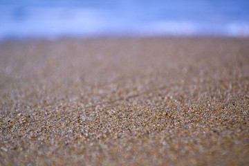 Fototapeta na wymiar sand texture on a tropical beach with a blurred sea background. 