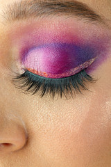 Obraz premium A close up of a beautiful purple eye makeup with glitter and multicolor transitions.