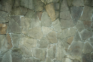 Close up hand crafted crooked old wall with many small and large stones like red sandstone and natural stones. Background