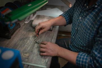 The master holds a screwdriver and repairs the scissors for the manicure