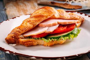 Croissant with ham and vegetables on a plate. Breakfast. Closeup