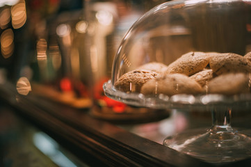 The restaurant serves cookies. Oatmeal cookies lie on a glass plate. A plate with a biscuit is on the display case.