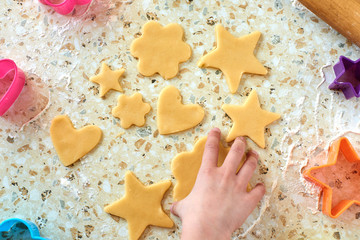 A child with his mother makes cookies, rolls out the dough and uses forms to make cookies.