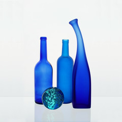 Still life with blue bottles and a glass ball on a white background