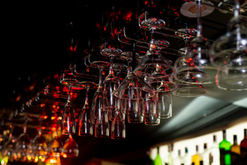 Wine glasses and martini hang above the bar counter at restaurant. Close-up photo.