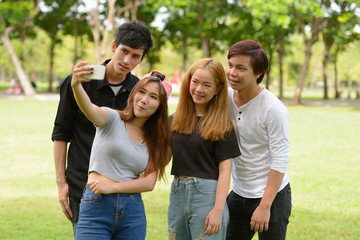 Happy young group of friends taking selfie together at the park