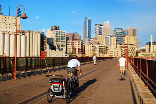 An adult man has special cargo in tow as he crosses the Stone Arch Bridge in Minneapolis