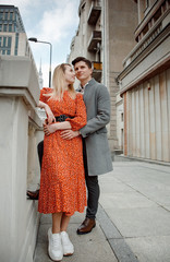 tourist couple in big city. The guy with the girl is hugging and happy. Girl in red dress kissing boy.