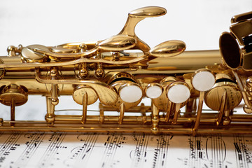 saxophone closeup with music sheet on a white background