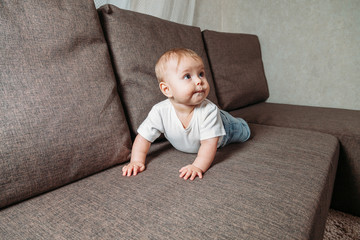 hildhood babyhood and people concept happy smiling little baby boy or girl crawling on sofa