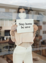 Young woman with paper sign looking through window