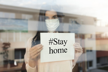 Young woman with paper sign looking through window