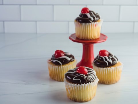 Closeup Of Fresh Yummy Chocolate Cupcakes With Cherry Against A Grey Blurry  Background