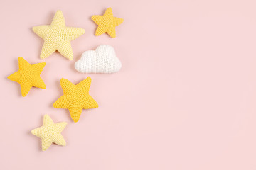 Knitted toy  yellow stars on pink background. Baby stuff and accessories. Flat lay, top view