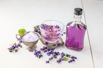 Cup of herbal violet violetta odorata tea with fresh spring blossom petals flowers on white  wooden...