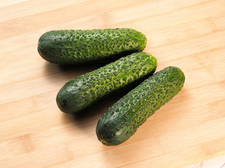 Three fresh green cucumbers on wooden backgound