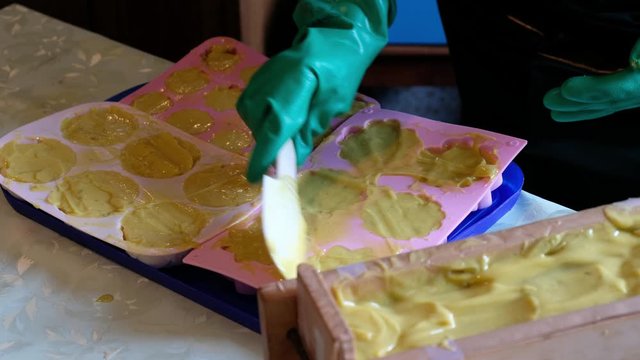 Frau mit Handschuhen stellt Seife in Silikonformen her