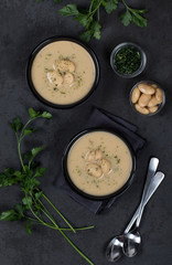 Bean cream soup with dill, parsley in a bowl on a dark background top view
