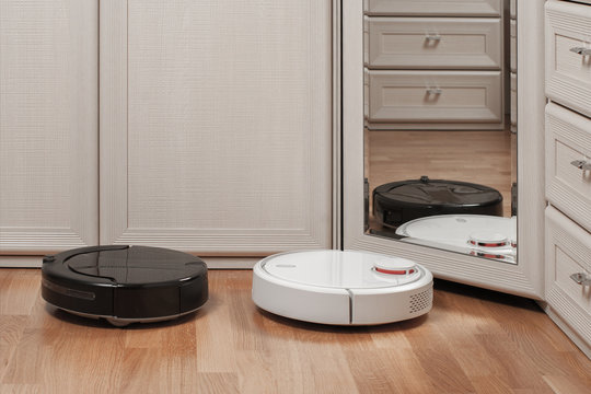 reflection of two different robotic vacuum cleaners running before mirror in bedroom. concept choosing household helper. modern smart appliance for cleaning house
