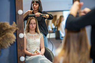 Girl hairdresser doing hairstyle in the form of spinning hair.