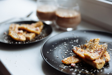 Homemade caramelized banana in black plate on white table, vegan dessert. Selective focus