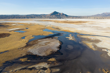 Puddle of alkaline water on Grimshaw Lake and Tecopa mountain along the Amargosa Valley create a colorful and forbidden desert scenery