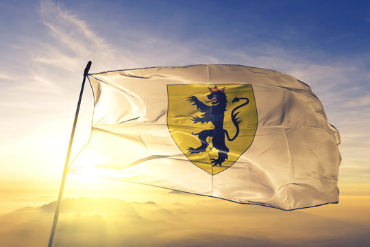 Fleurus of Hainaut of Belgium flag waving on the top sunrise mist fog