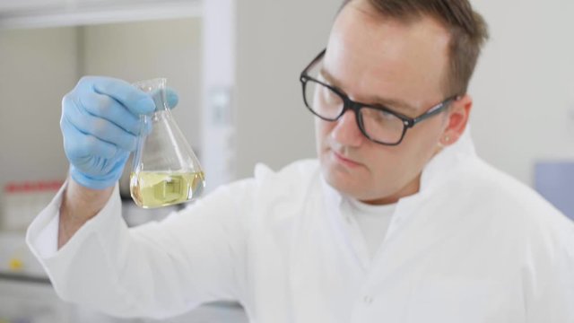 Close up of chemist working with hemp CBD oil and tablet in laboratory