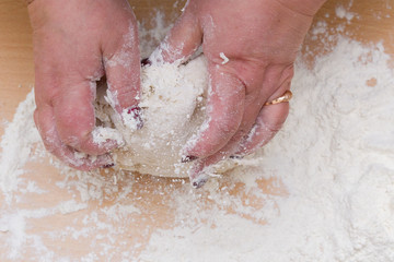 Fototapeta premium Kneading dough with flour on a wooden table at home