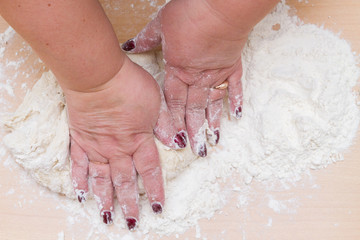 Fototapeta premium Kneading dough with flour on a wooden table at home