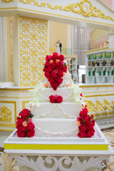 Colorful cakes for the occasion. Close-up . Beautiful Wedding Cake with Rose Flowers Decoration . Rose covered wedding cake at reception table . Wedding cake with red roses flowers .