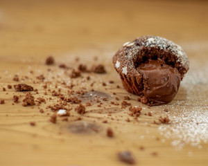 Cocoa muffins with a heart of chocolate cream and icing sugar, placed on a wooden table