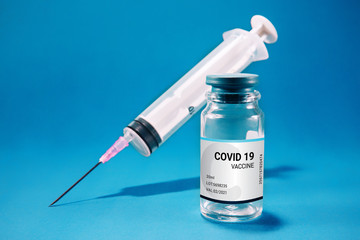 Coronavirus vaccination concept. Covid-19 medicine bottle with syringe, isolated against blue...