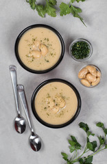 Bean cream soup with dill, parsley in a bowl on a light gray background top view