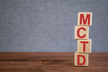 Abbreviation MCTD (Mixed connective tissue disease) text acronym on wooden cubes on dark wooden...