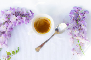 Fototapeta na wymiar white cup of coffee with strawberries and purple flowers on a table ready for breakfast