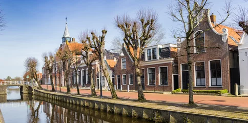 Foto auf Leinwand Panorama of historic town hall and old houses at the canal in Balk, Netherlands © venemama