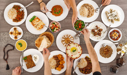 Iftar. Arabic family dinner after fasting. People sharing plates by hands. Ramadan Kareem, Eid Mubarak. Top view of table with food. Lebanese cuisine. Muslim people. - 339326190