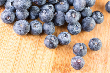 Fresh blueberry in white plate photographed against wooden background