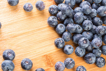 Fresh blueberry in white plate photographed against wooden background