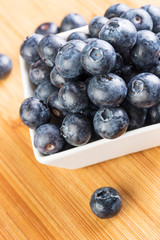 Fresh blueberry in white plate photographed against wooden background