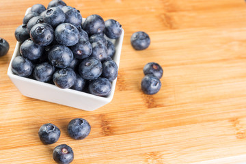 Fresh blueberry in white plate photographed against wooden background