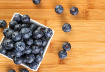 Fresh blueberry in white plate photographed against wooden background