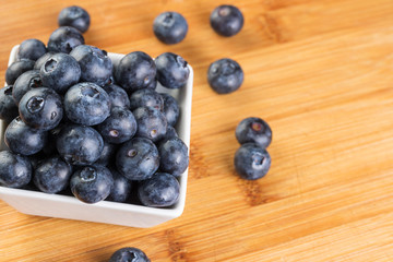 Fresh blueberry in white plate photographed against wooden background